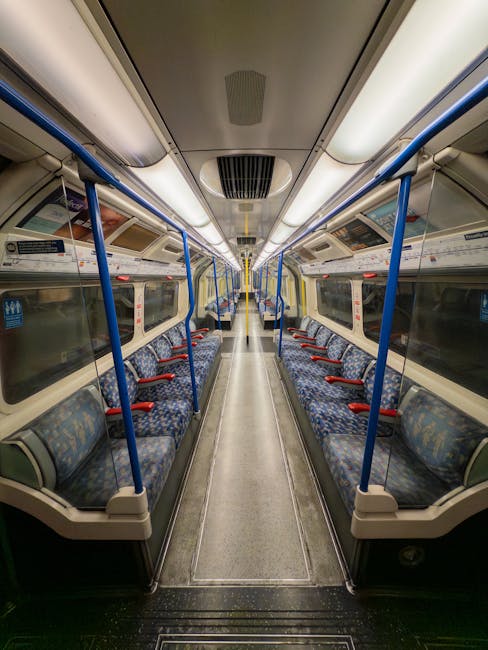 An underground station platform at High Barnet tube station with clean, tiled floors and smooth, curved white walls. The platform features a row of advertisements displayed along the wall, some showca